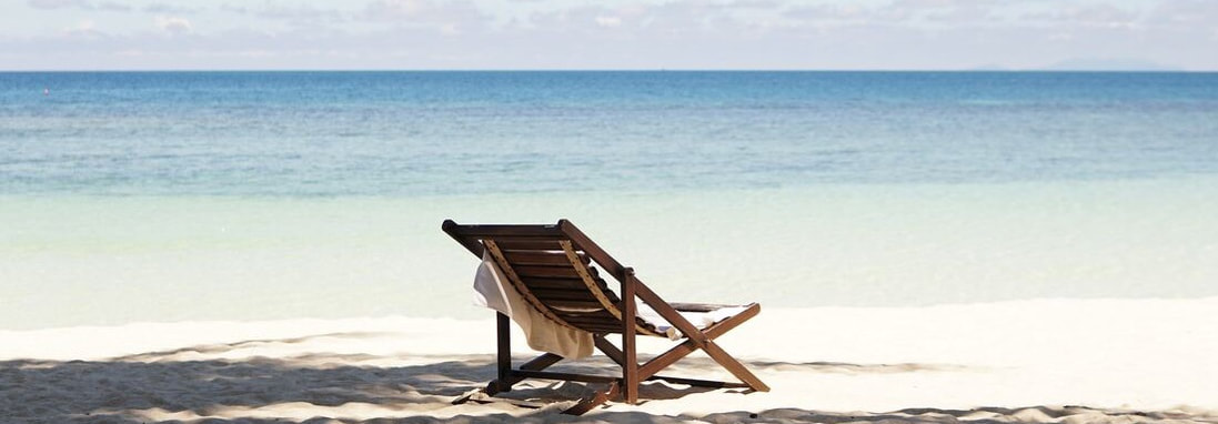 A chair on the beach near a calm sea.